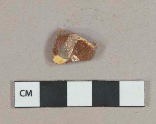 Yellow on reddish brown slip decorated redware vessel body fragment