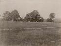 Two men in a field, possibly surveying mounds