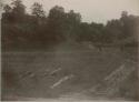 Men in a field, possibly surveying mounds