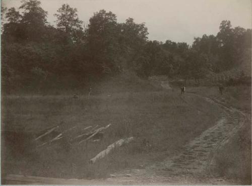 Men in a field, possibly surveying mounds