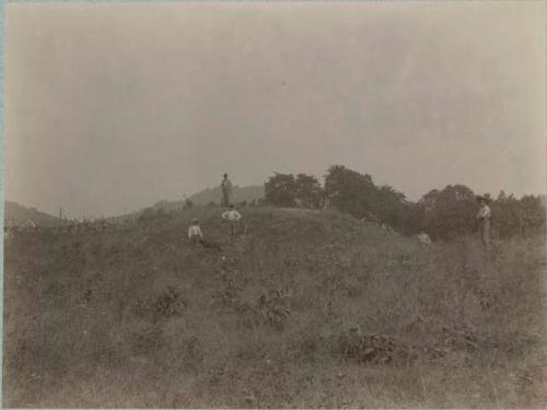 Farm landscape with men standing on top of hill