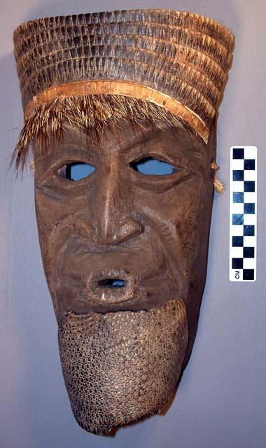 Wooden mask with flattened nose, protruding lips.  Beard and hair represented by