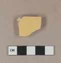 Undecorated yellow ware vessel body fragment, buff paste with gray paste inclusion, possible mochaware