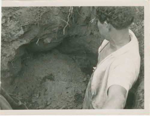 Man standing in excavated trench or grave