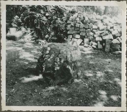 Stone sculpture with crumbling wall in background