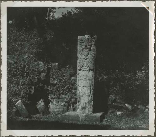 Upright stela in front of crumbling stone wall