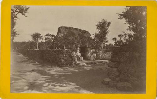 Thatched-roof building, stone walls, and a group of men