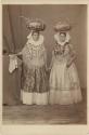 Women in traditional dress carrying bowls on their heads