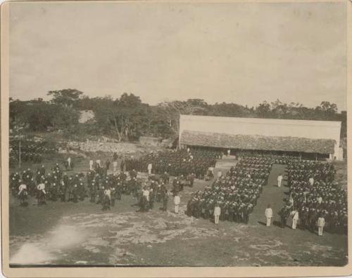 Soldiers and officers in parade formation in an open area in front of a building