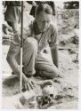 Hallam Movius, Jr. kneeling, looking at skull at excavation site