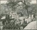 Group of people, mostly women, standing outside the fence (print is a cropped image)