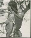 Woman carrying a baby on her back, with baobab tree in background (print is a cropped image)