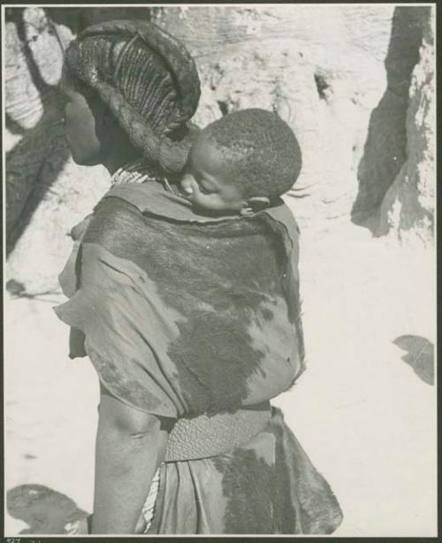 Woman carrying a baby on her back, with baobab tree in background (print is a cropped image)