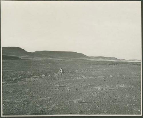 Person sitting, with buttes in background (print is a cropped image)