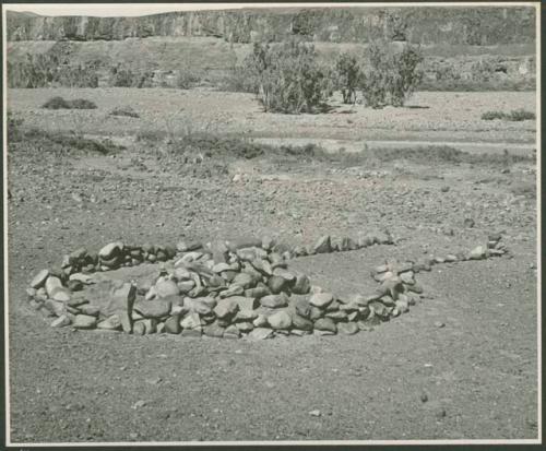 Pile of stones in circle with space for entrance (print is a cropped image)