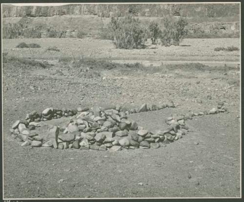 Pile of stones in circle with space for entrance (print is a cropped image)