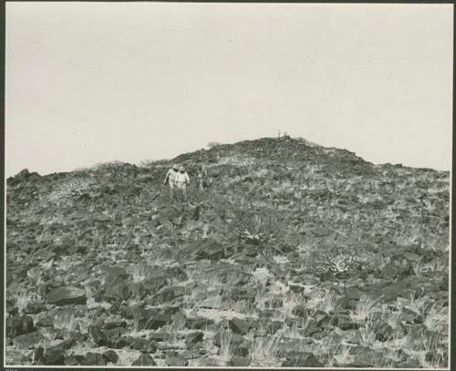 Three men walking down a hill, and two men standing at the top