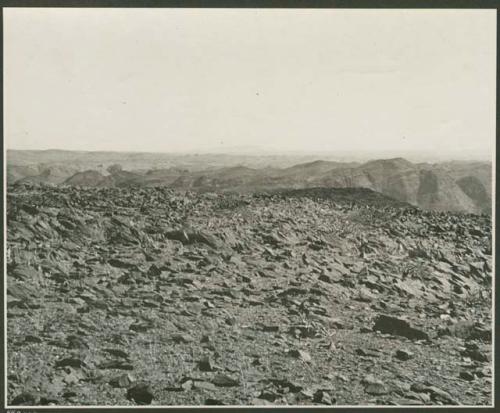 Rocky landscape with hills in the distance (print is a cropped image)