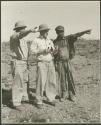 Three men standing and looking at something in the distance (print is a cropped image)