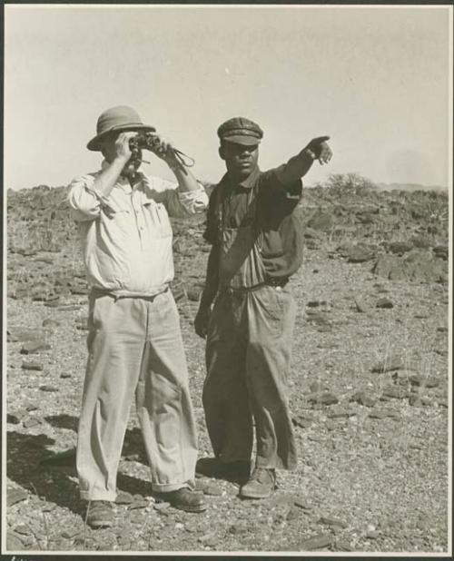 Two men standing and looking at something in the distance (print is a cropped image)