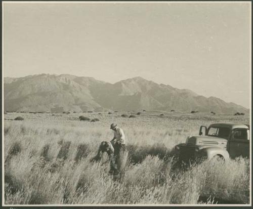 Two expedition members standing near the truck (print is a cropped image)