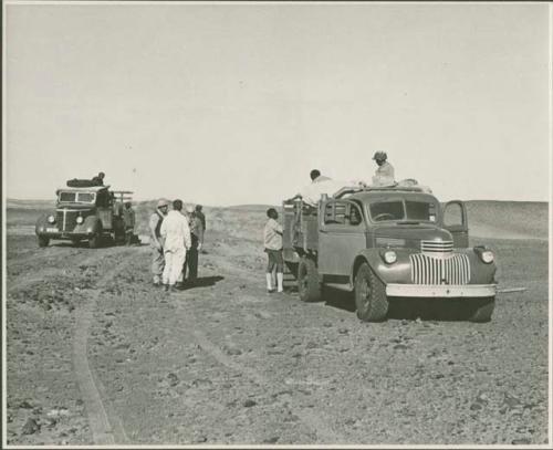 Expedition members standing on and next to trucks (print is a cropped image)