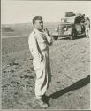 Expedition member standing, with others next to a truck in the background (print is a cropped image)