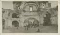 Large building in town with people standing under arch, possibly Antigua