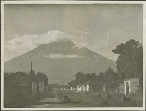 Road through village with view of mountain in background, possibly Antigua