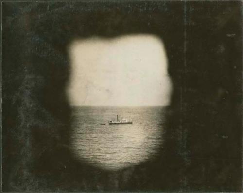 Through back window of Castillo, view of boat in the water, in Tulum