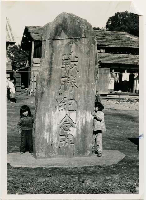 Children and stone monument with Shimenawa or sacred rope