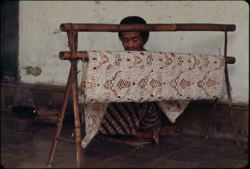 Court servant making batik