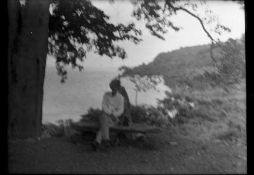 Man sitting on a bench, with shoreline in background