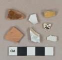 3 pearlware vessel body fragments, 1 with light blue transfer decoration, white paste; 1 white undecorated porcelain vessel body fragment, white paste; 2 brown lead glazed redware vessel body fragments; yellow possible paint chip, laminated