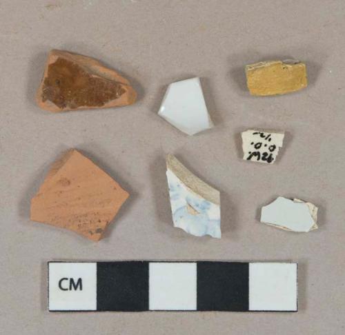 3 pearlware vessel body fragments, 1 with light blue transfer decoration, white paste; 1 white undecorated porcelain vessel body fragment, white paste; 2 brown lead glazed redware vessel body fragments; yellow possible paint chip, laminated