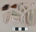 2 light aqua flat glass fragments; 2 colorles flat glass fragments; 6 colorless vessel glass body and rim fragments, 1 with embossed lettering "...UB... / ...RVA... / ...R..."; 1 colorless glass stemware stem fragment; 2 amber glass vessel body fragments, likely bottle glass