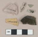 Various glass fragments: 1 dark olive glass vessel fragment; 2 aqua glass vessel fragment; colorless glass vessel fragment; 1 light green vessel glass fragment; heavily patinated
