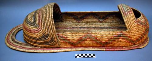 Basketry cradle. Made of bear grass. Geometric designs (zig-zags and lines).