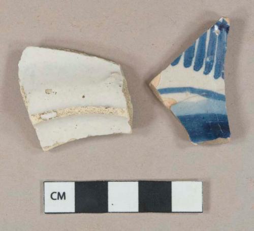 Blue on white handpainted tin-glazed earthenware vessel body fragment, orange buff paste; White undecorated tin-glazed earthenware vessel body fragment, buff paste