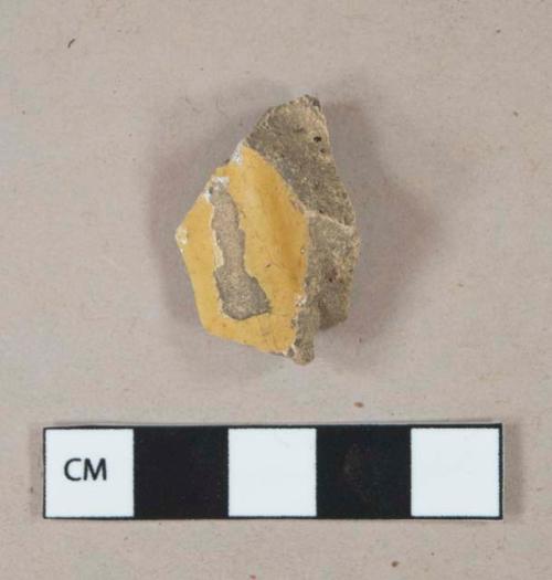 Yellow lead glazed earthenware vessel base fragment, buff paste, likely Staffordshire slip