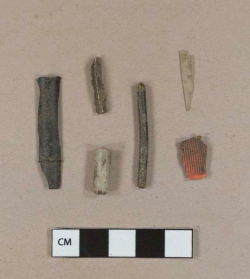 Plastic fragments, 3 black; 1 colorless clear; 1 light gray; 1 orange, likely cap