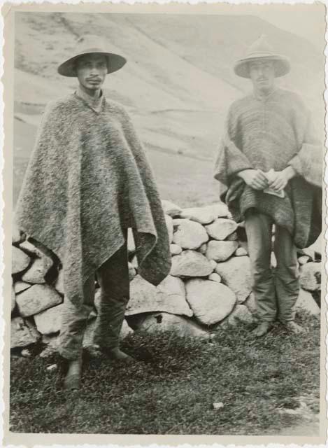 Two men standing in front of rock wall