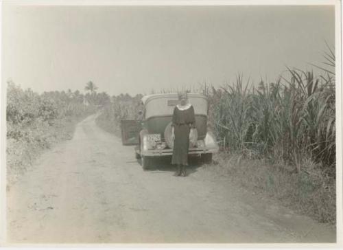 Woman in standing next to automobile at side of road to Puerto Caribe