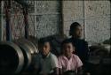 Man and two boys sitting next to old gamelan at Grebeg festival