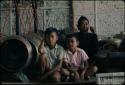 Man and two boys sitting next to old gamelan at Grebeg festival