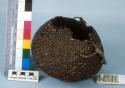 Twined basket with cloth handle. Made of bear grass and covered with pitch.