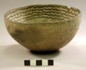 Hemispherical grey pottery bowl with black linear designs inside, chipped rim