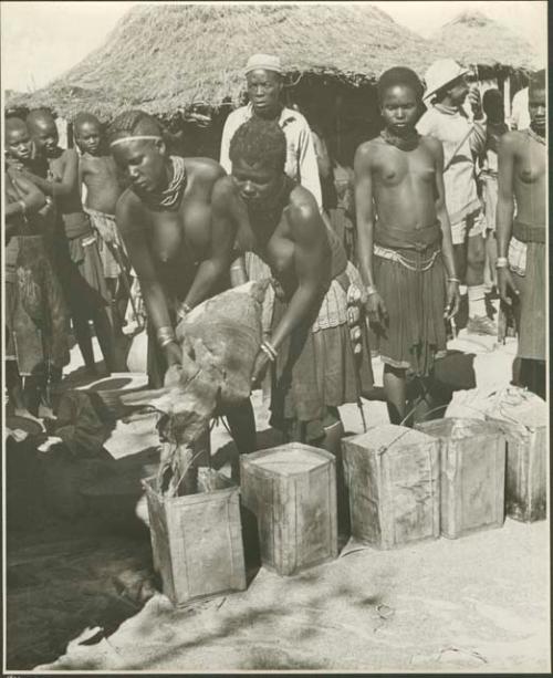 Women pouring grain from sack into tins (print is a cropped image)