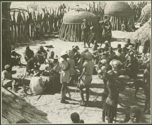 Group of people standing inside a kraal (print is a cropped image)