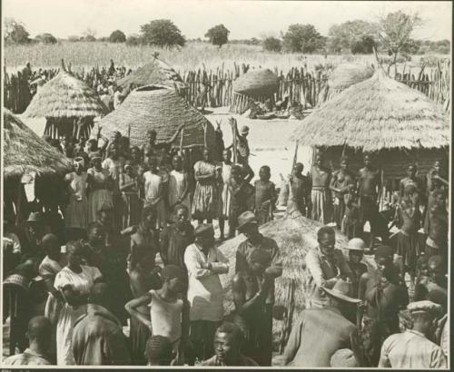 Group of people standing inside a kraal (print is a cropped image)